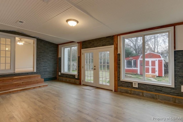 interior space featuring ceiling fan, french doors, brick wall, hardwood / wood-style floors, and vaulted ceiling