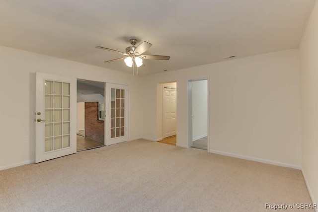 carpeted spare room featuring ceiling fan and french doors