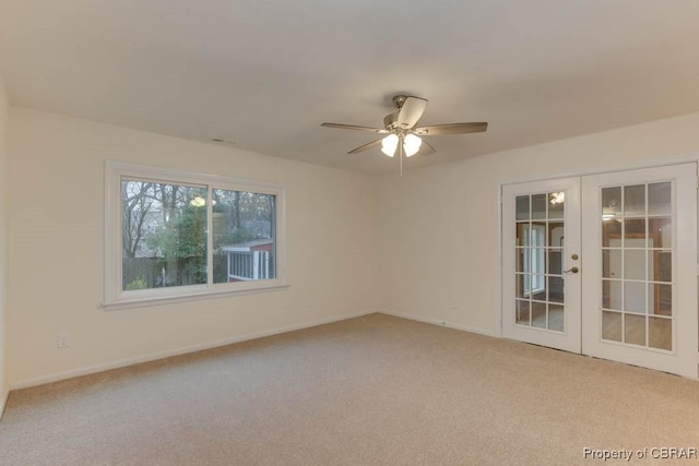 empty room with ceiling fan, light colored carpet, and french doors