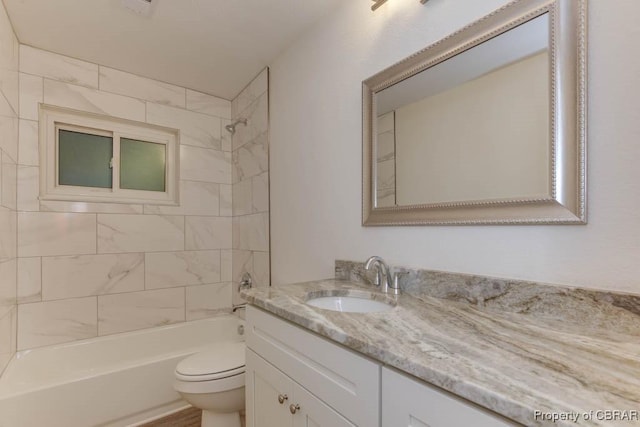 full bathroom with vanity, tiled shower / bath combo, and toilet