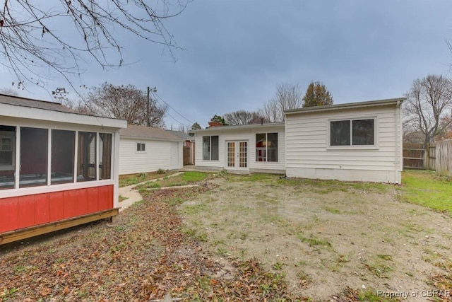 rear view of property featuring a yard, a sunroom, and french doors