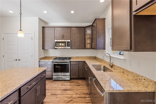 kitchen with dark brown cabinetry, stainless steel appliances, sink, decorative light fixtures, and light hardwood / wood-style flooring