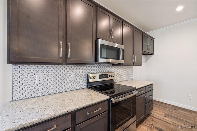 kitchen with tasteful backsplash, ornamental molding, dark brown cabinetry, stainless steel appliances, and light hardwood / wood-style floors