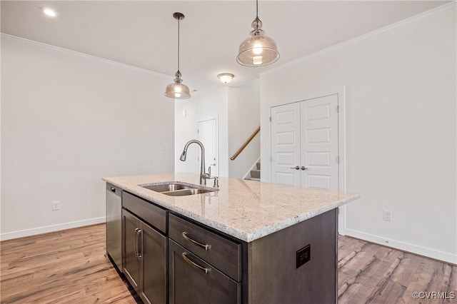 kitchen featuring ornamental molding, sink, dishwasher, light hardwood / wood-style floors, and an island with sink