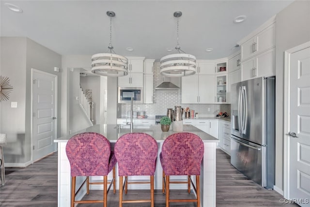 kitchen with stainless steel appliances, white cabinetry, a center island with sink, and a notable chandelier