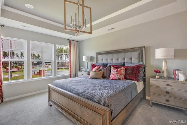 carpeted bedroom with a raised ceiling, ornamental molding, and an inviting chandelier