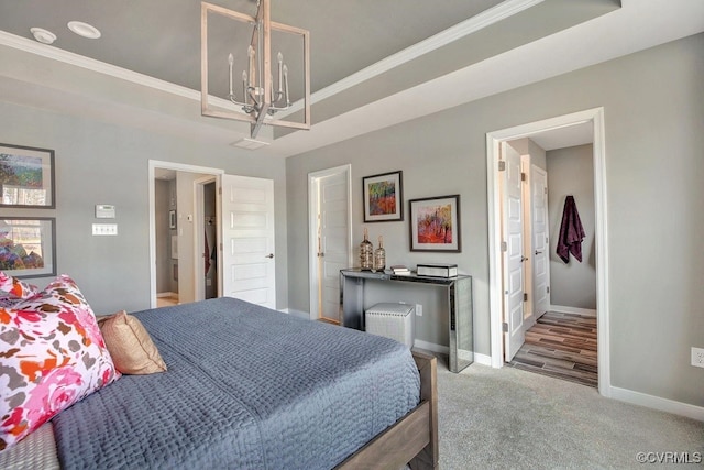 bedroom with carpet flooring, a raised ceiling, ensuite bathroom, a chandelier, and ornamental molding