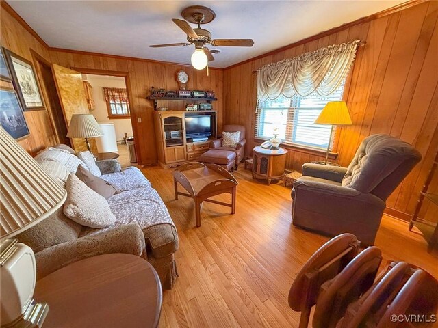 living room with ceiling fan, crown molding, wooden walls, and light hardwood / wood-style flooring