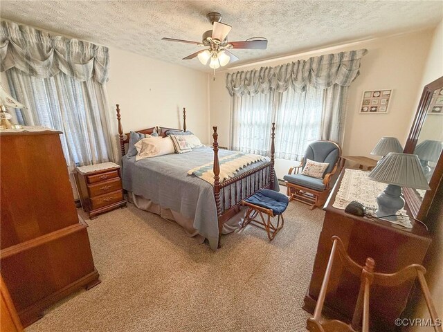 bedroom featuring a textured ceiling, light colored carpet, and ceiling fan