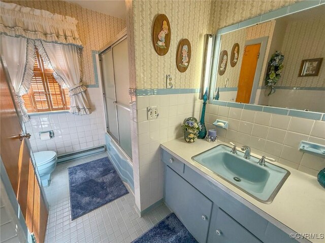 bathroom with baseboard heating, tile patterned flooring, vanity, a shower with shower door, and tile walls