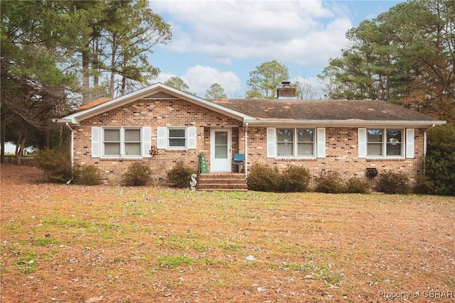 ranch-style home featuring a front yard, brick siding, and a chimney