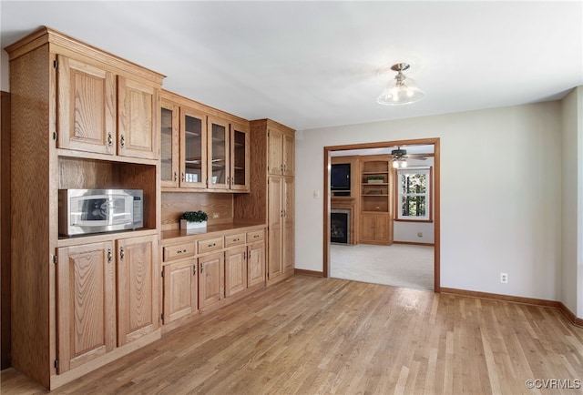 11741 Riverpark Dr, Chesterfield, VA 23838 - kitchen featuring stainless steel microwave, a fireplace, light wood-style flooring, and baseboards
