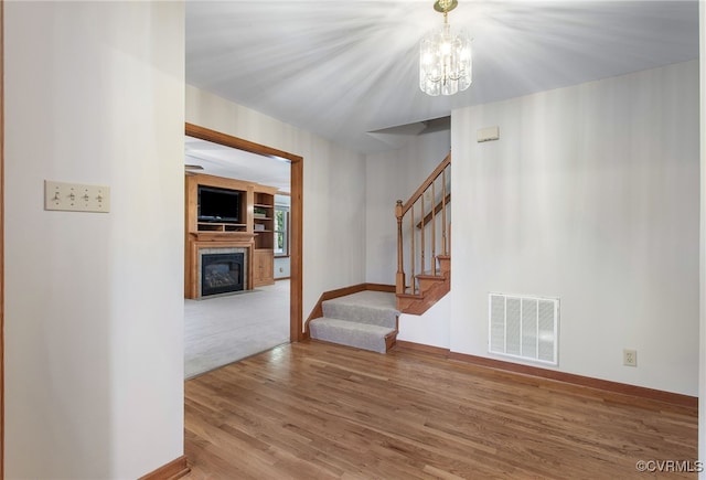 11741 Riverpark Dr, Chesterfield, VA 23838 - interior space with a glass covered fireplace, an inviting chandelier, stairway, visible vents, and wood finished floors