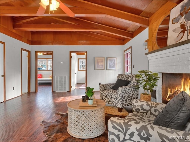 living room featuring vaulted ceiling with beams, hardwood / wood-style flooring, a brick fireplace, and ceiling fan