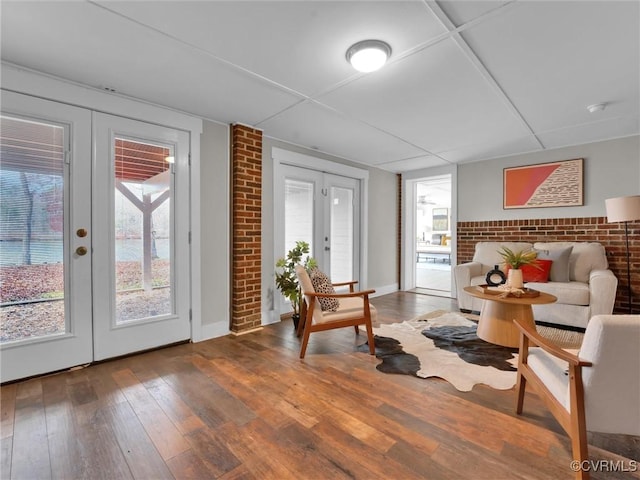 living area with french doors, hardwood / wood-style floors, and brick wall