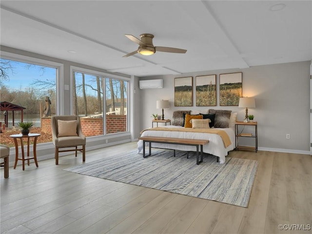 bedroom featuring light hardwood / wood-style floors, an AC wall unit, and ceiling fan