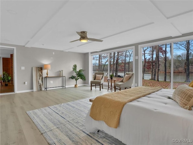 bedroom featuring ceiling fan, access to exterior, light wood-type flooring, and a water view