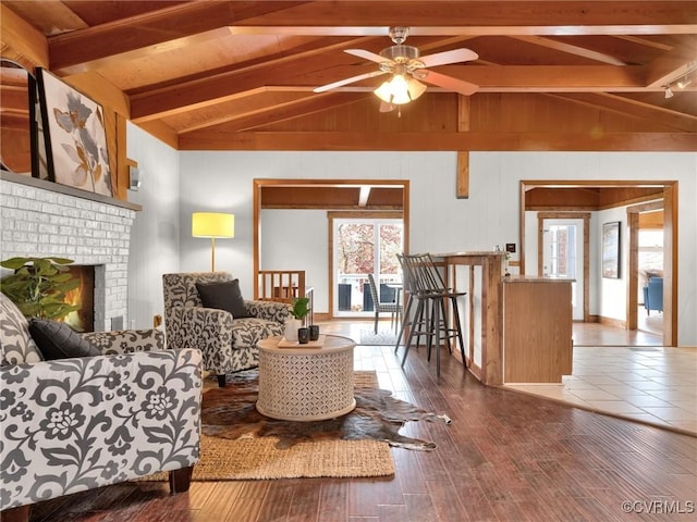 living room with hardwood / wood-style flooring, vaulted ceiling with beams, ceiling fan, and a brick fireplace