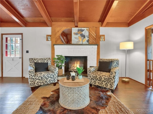 sitting room featuring beamed ceiling, dark wood-type flooring, and a brick fireplace