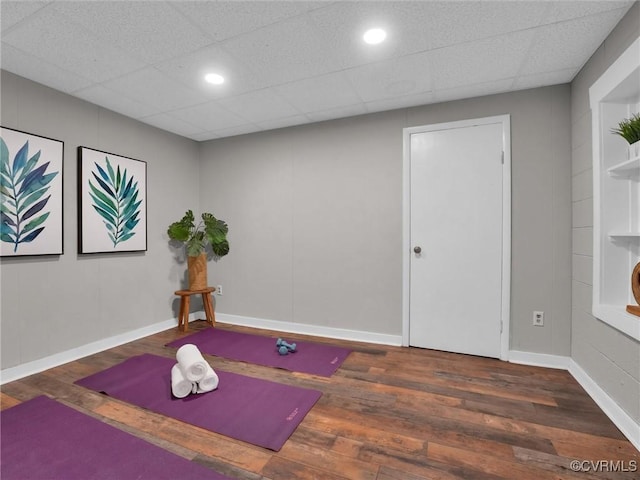 exercise room featuring dark hardwood / wood-style floors and a drop ceiling