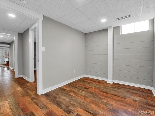 empty room featuring dark hardwood / wood-style flooring and a drop ceiling