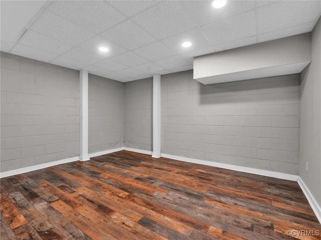 basement with dark hardwood / wood-style flooring and a drop ceiling