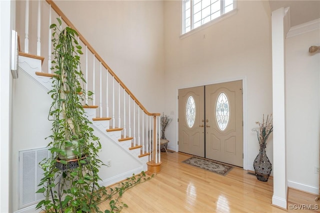 entryway with a high ceiling, ornamental molding, and hardwood / wood-style floors