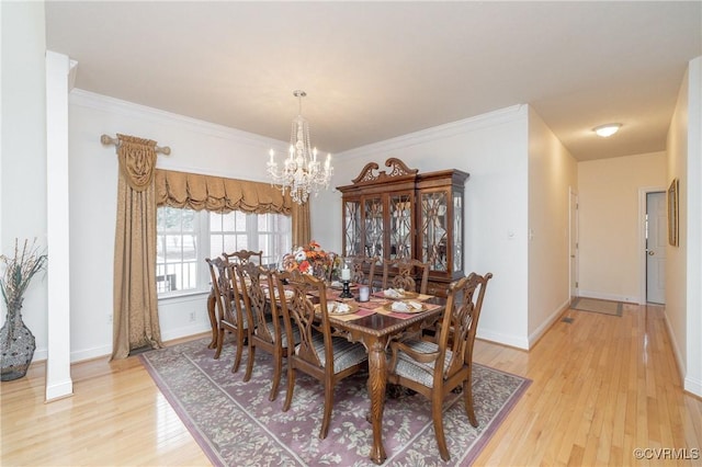 dining space with light wood-type flooring, crown molding, and a chandelier