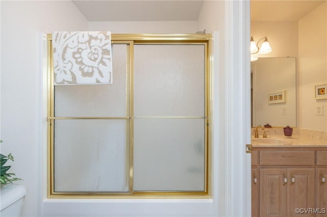 bathroom featuring toilet, vanity, and a shower with door