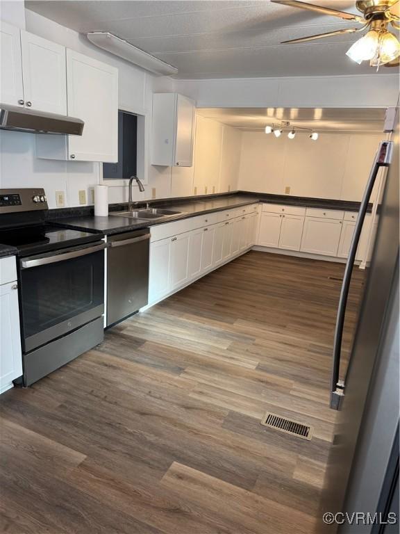 kitchen with dark wood-type flooring, white cabinets, and stainless steel appliances