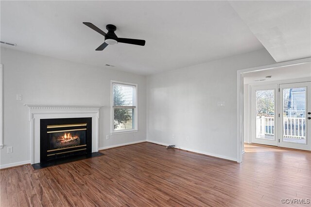 unfurnished living room featuring a wealth of natural light, dark wood-type flooring, and ceiling fan