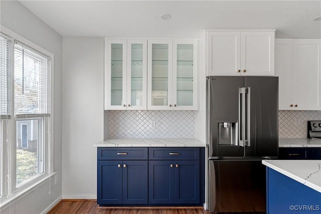 kitchen featuring stainless steel fridge, backsplash, white cabinetry, and hardwood / wood-style floors