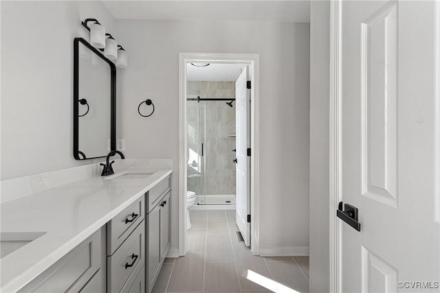 bathroom with tile patterned flooring, a shower with door, vanity, and toilet