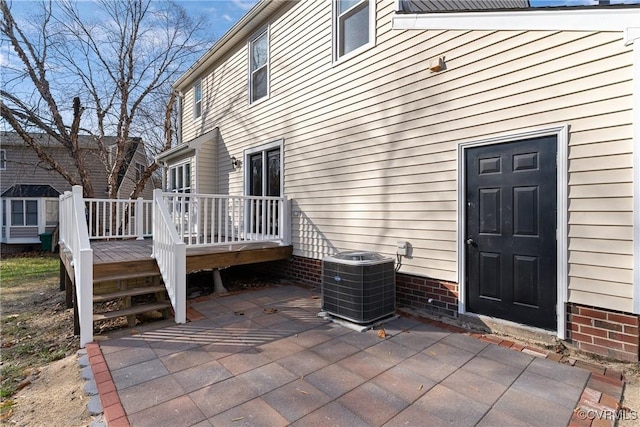 view of exterior entry with cooling unit, a patio area, and a deck