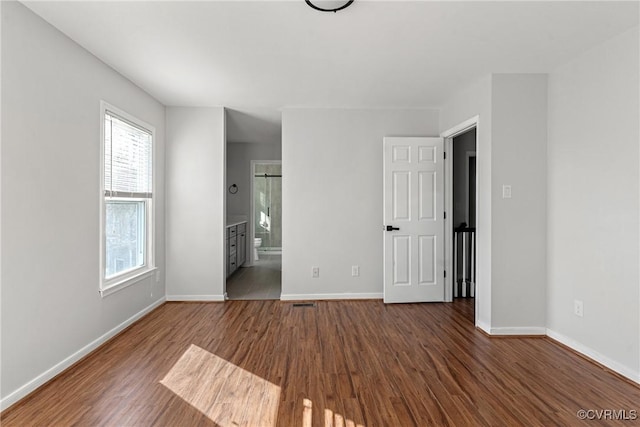 unfurnished bedroom with dark hardwood / wood-style flooring and ensuite bath