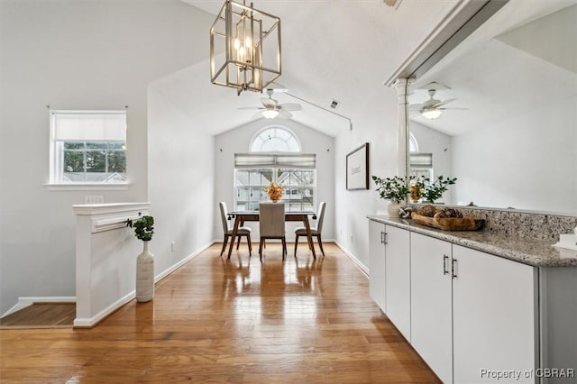 dining space featuring wood-type flooring, ceiling fan with notable chandelier, a wealth of natural light, and lofted ceiling