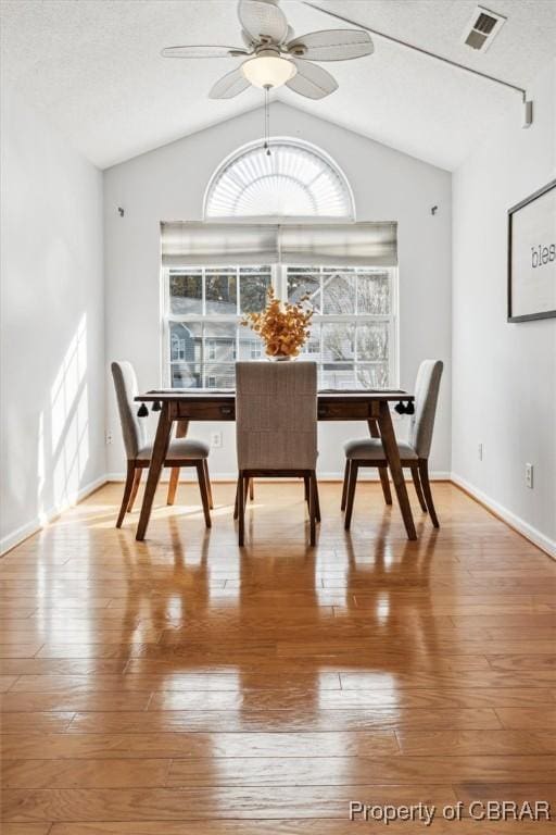 dining space with hardwood / wood-style flooring, ceiling fan, and lofted ceiling