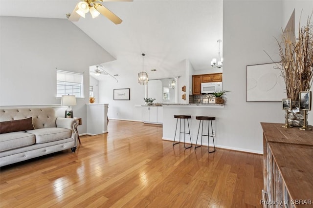 living room with high vaulted ceiling, light hardwood / wood-style flooring, and ceiling fan