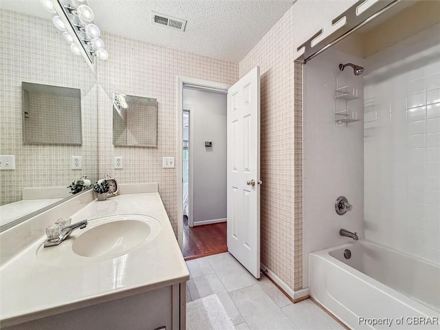 bathroom with tile patterned flooring, shower / bathing tub combination, a textured ceiling, vanity, and tile walls