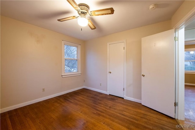 unfurnished bedroom featuring multiple windows, ceiling fan, and dark hardwood / wood-style flooring