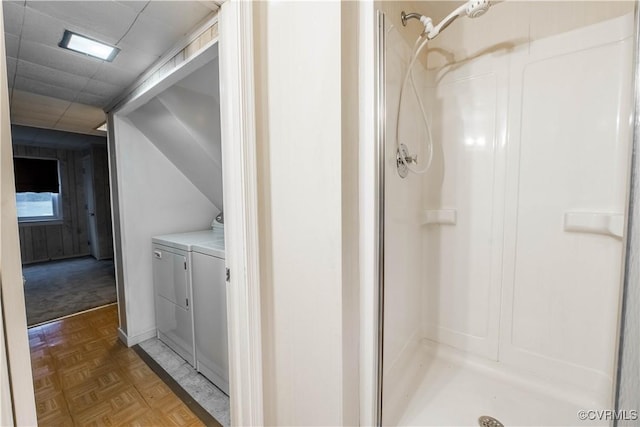 bathroom with washer and clothes dryer, a shower, and parquet flooring