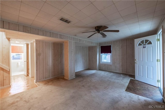 interior space featuring ceiling fan and wood walls