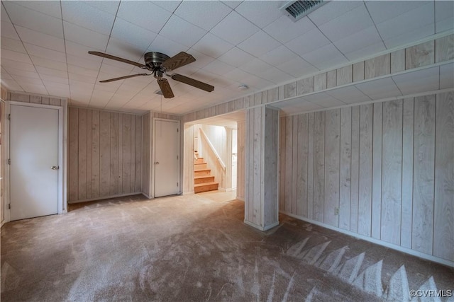 unfurnished living room with carpet flooring, ceiling fan, and wooden walls