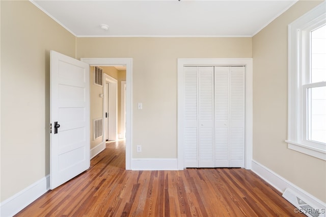 unfurnished bedroom with ornamental molding, a closet, and dark wood-type flooring