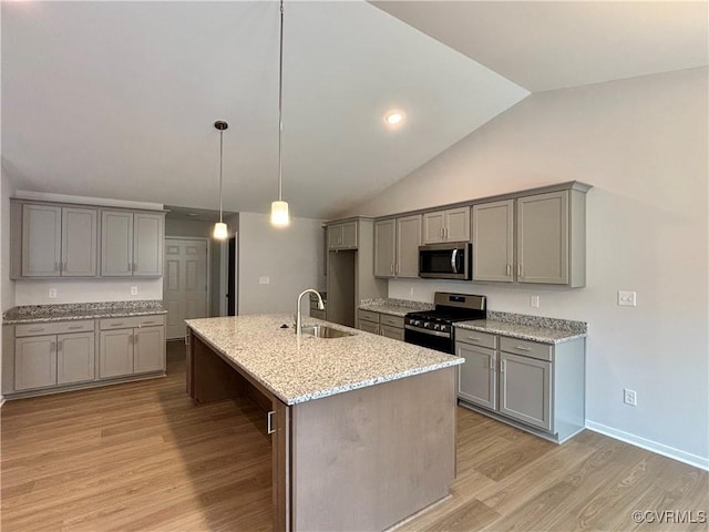 kitchen featuring sink, stainless steel appliances, lofted ceiling, gray cabinets, and a center island with sink