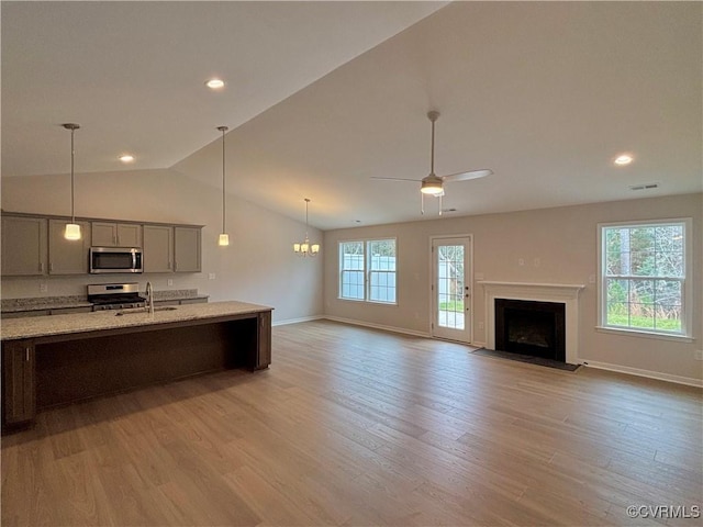 kitchen with light stone countertops, appliances with stainless steel finishes, plenty of natural light, and lofted ceiling