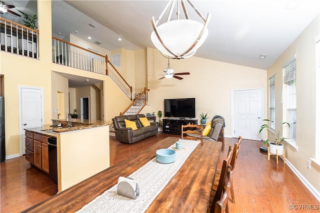 dining room with hardwood / wood-style floors, ceiling fan, sink, and high vaulted ceiling