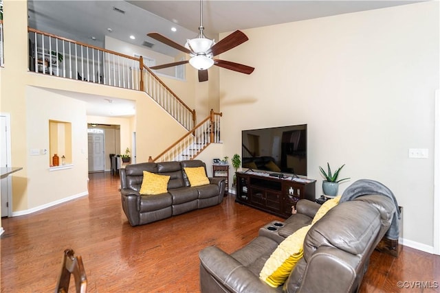 living room with hardwood / wood-style floors, a towering ceiling, and ceiling fan