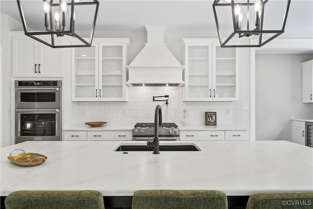 kitchen featuring a breakfast bar, custom range hood, tasteful backsplash, and a chandelier