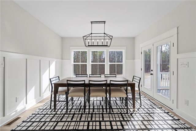 dining area featuring hardwood / wood-style floors, a chandelier, and french doors